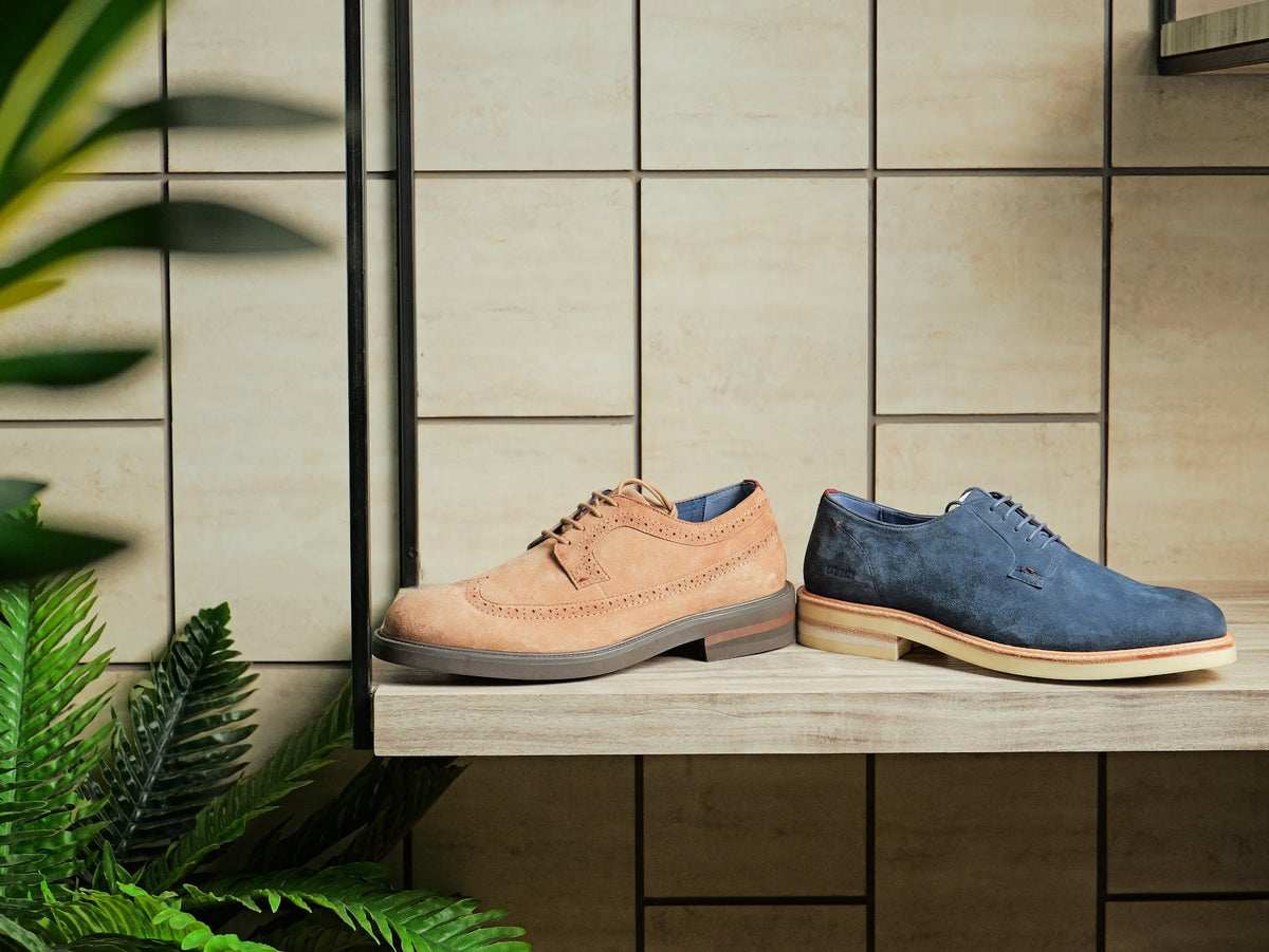 A men’s suede brogue and derby on a showroom shelf
