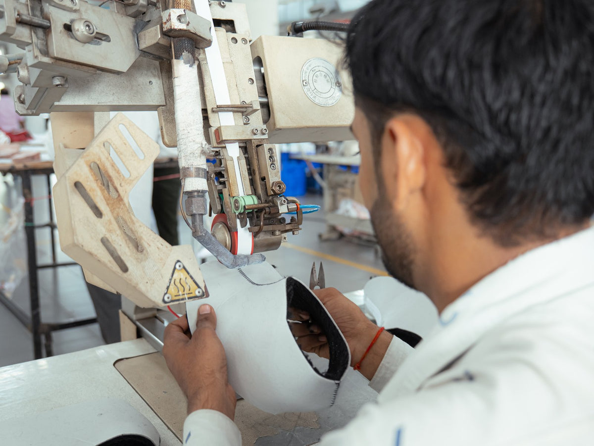 An operator guiding an upper seam through a seam-sealing machine
