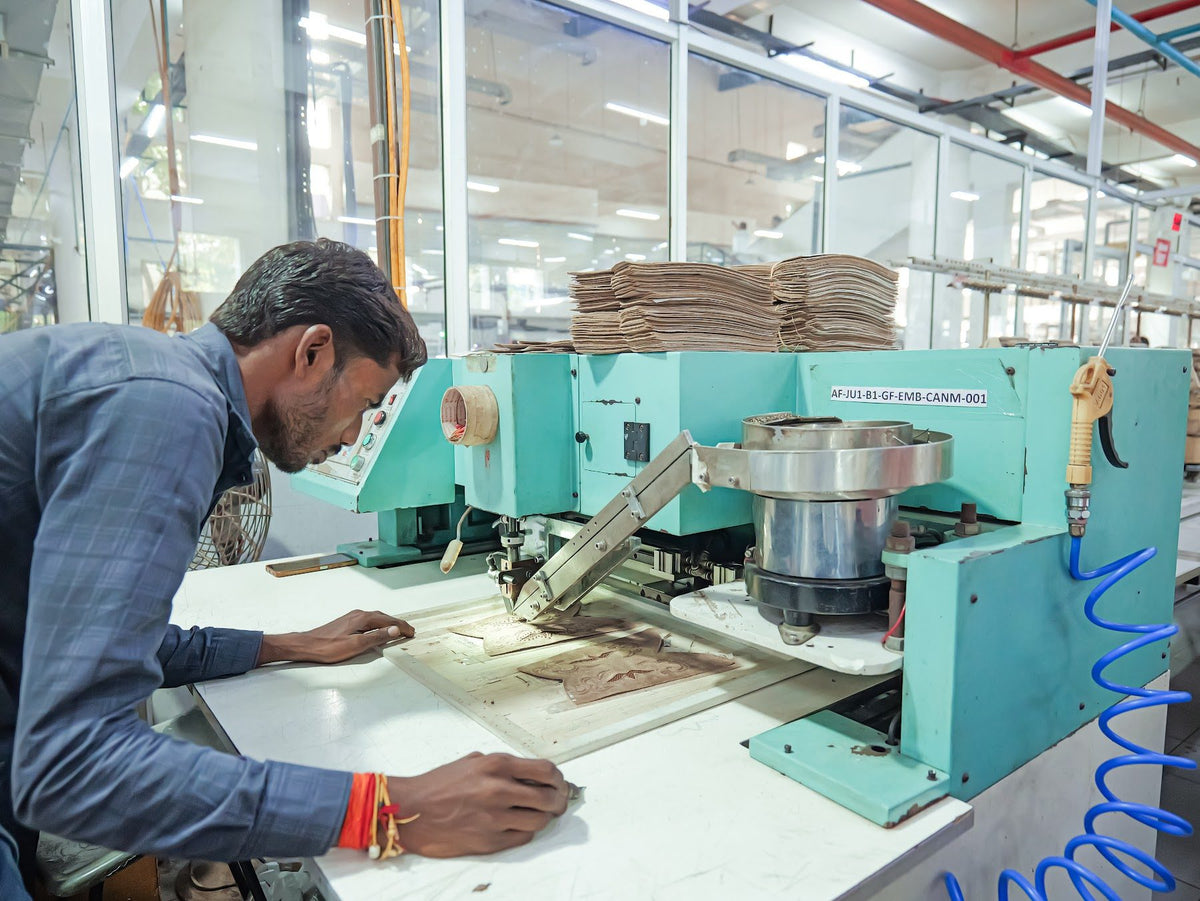 An operator guiding an upper through a pattern-stitching machine