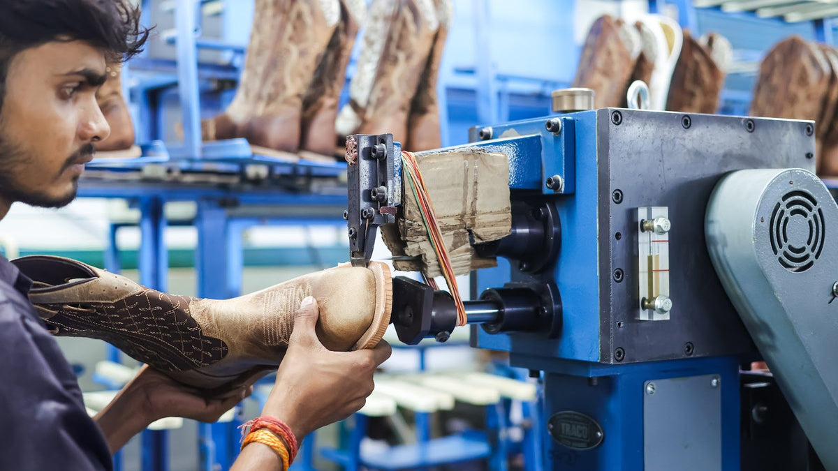 An AFPL operator works the toe of a Western boot at a machine, with finished boots on the rack behind