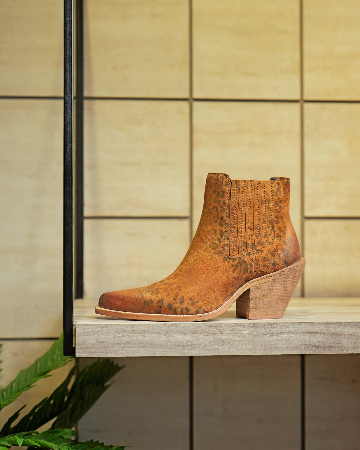 A printed suede ankle boot with a block heel on a display shelf