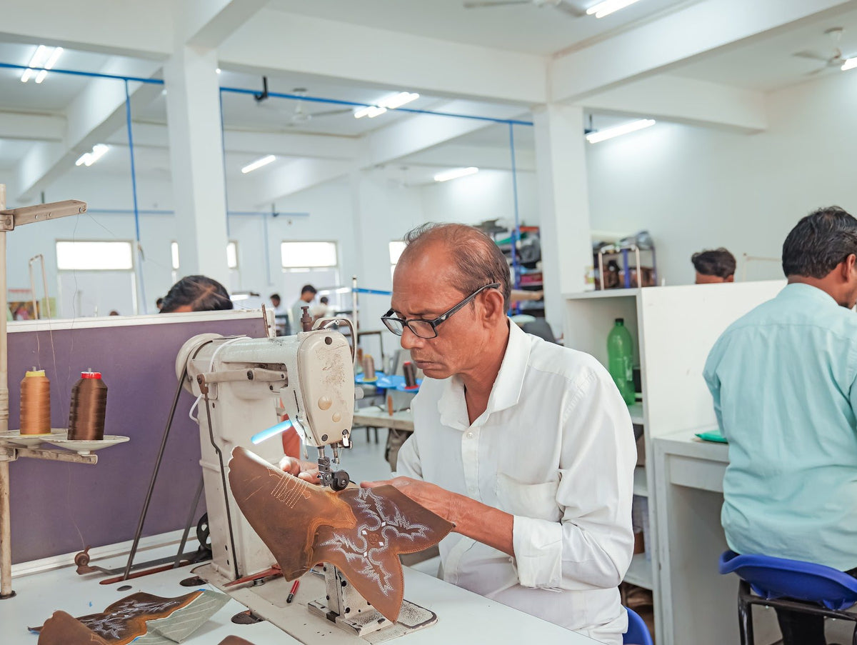 A sample maker stitching an embroidered Western boot shaft in a closing pod