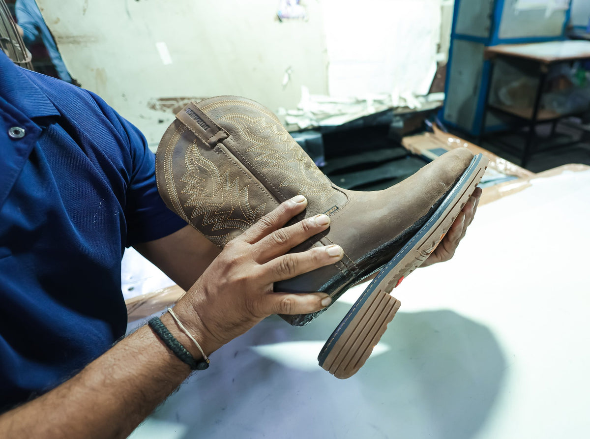 The sole edge of a finished Western boot checked by hand