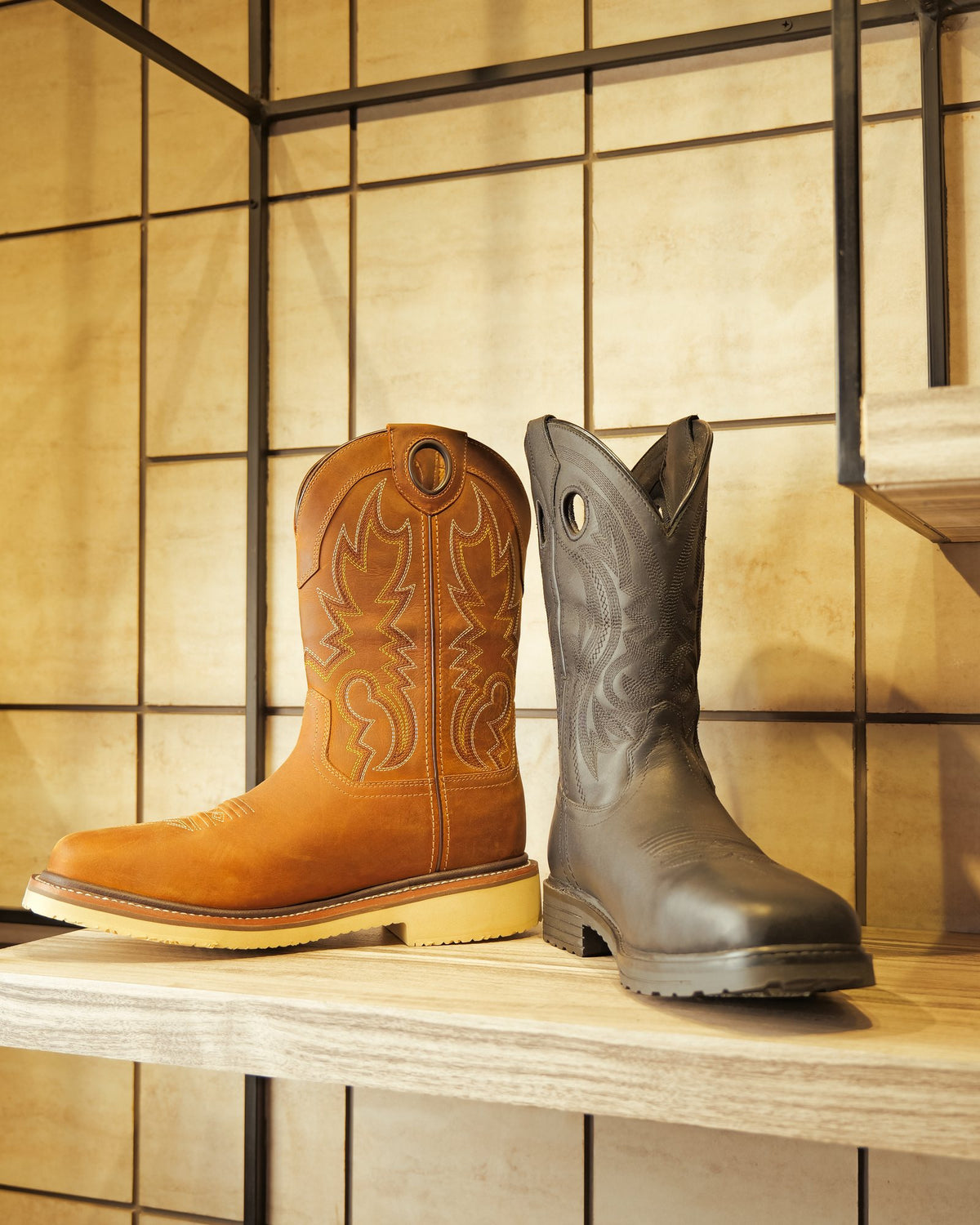 A tan and a dark brown pull-on boot on a display shelf