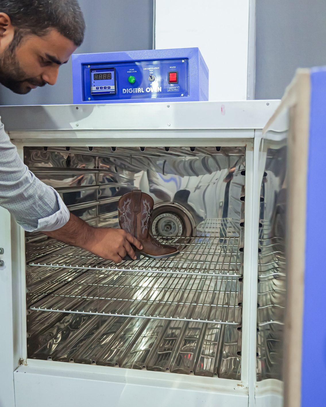 A technician placing finished footwear in a laboratory ageing oven
