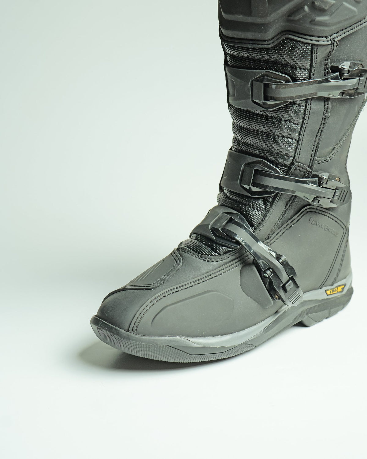 A black bike-riding boot with buckles and protective panels, in close-up