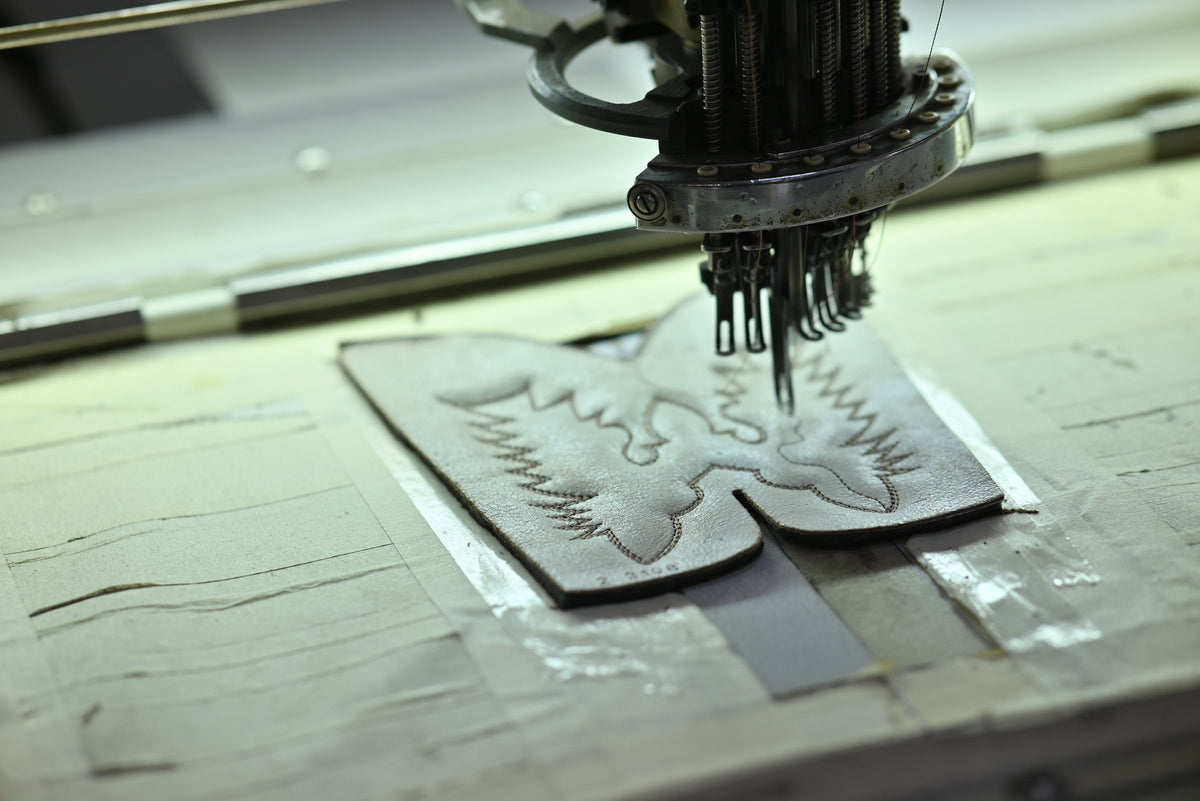 A multi-needle embroidery head stitching a pattern on a flat Western shaft panel