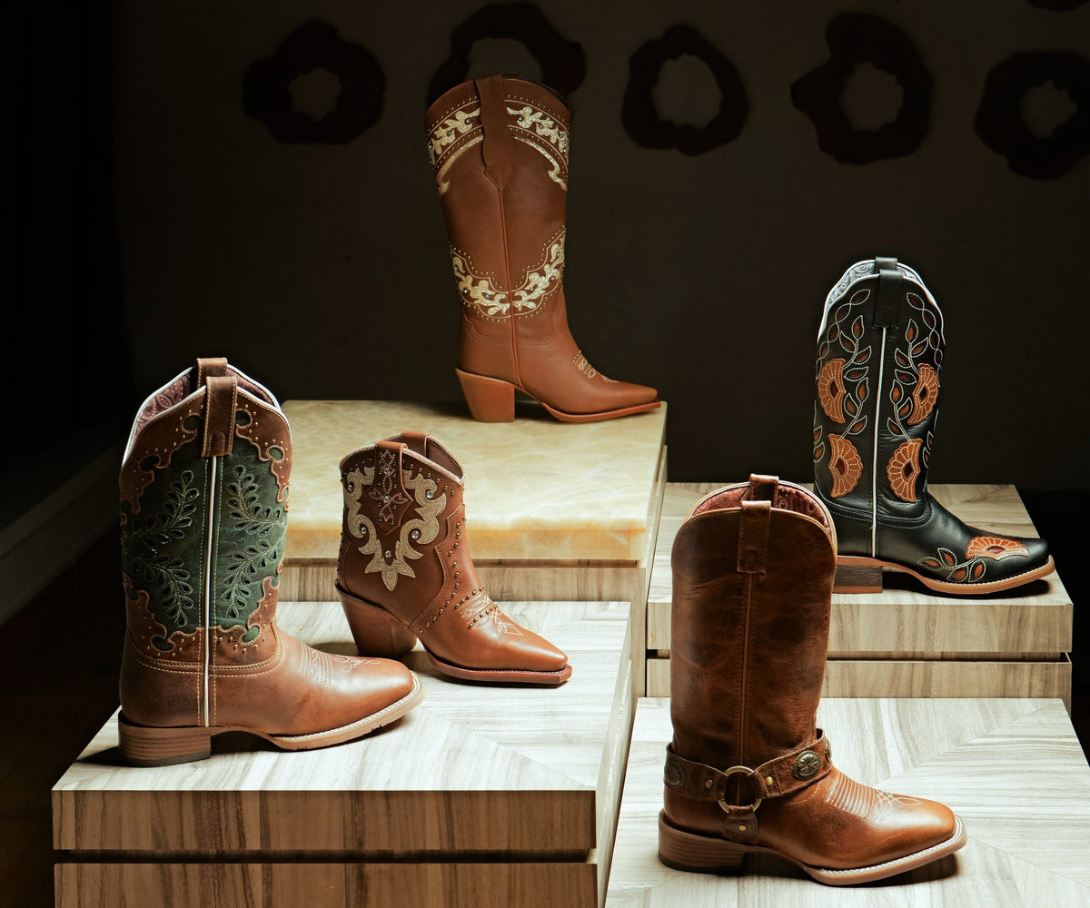 Five Western boots with embroidered and inlaid shafts on display plinths