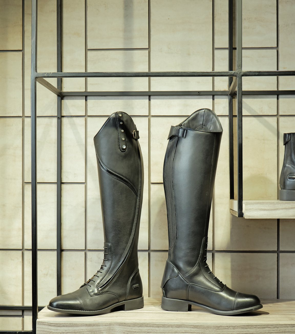 A lace-front and a tall black leather horse-riding boot on a showroom shelf