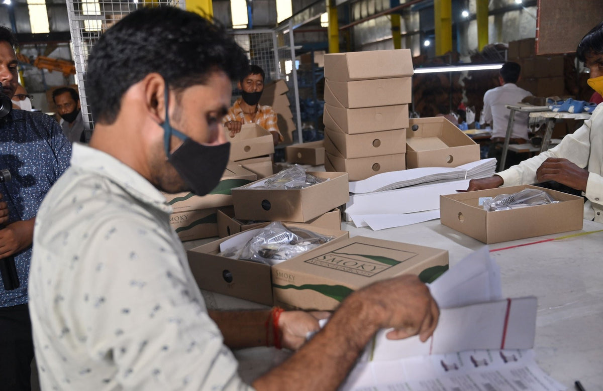A packer checking boxed pairs and carton labels before dispatch