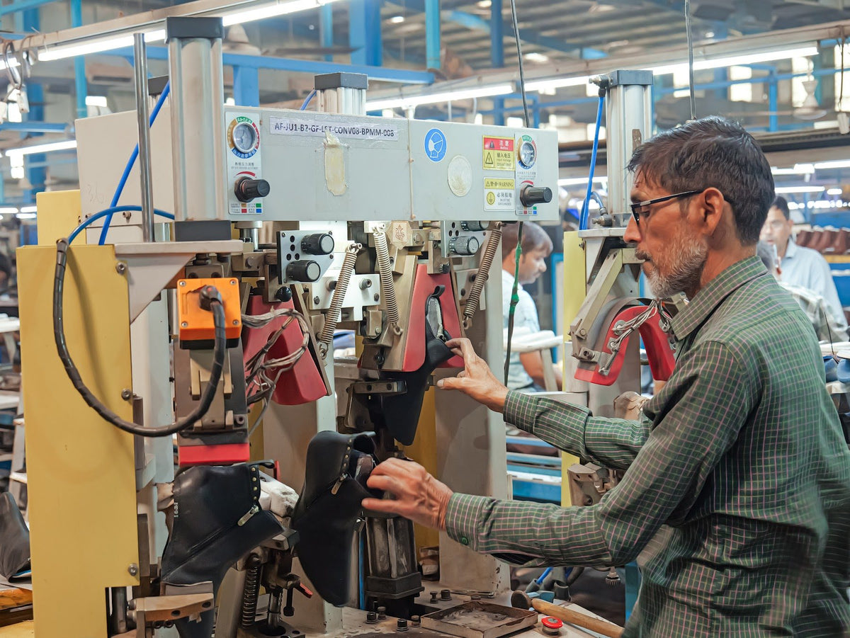 An operator at a toe-lasting machine with a boot on the last