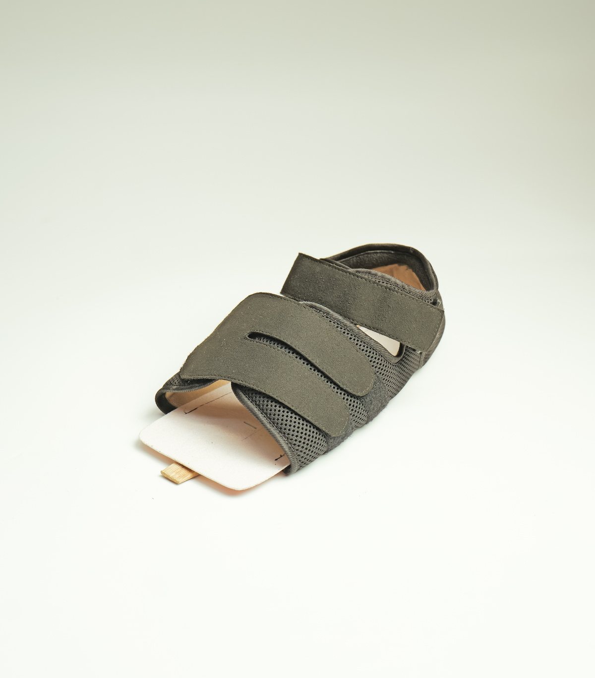 An orthopaedic shoe in breathable mesh with hook-and-loop straps and a rigid base