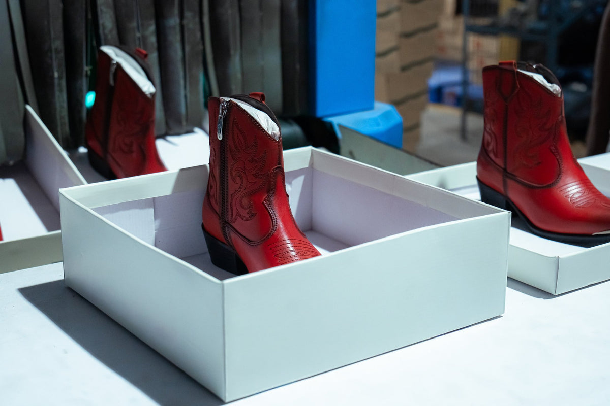 Red Western boots packed into white boxes for dispatch