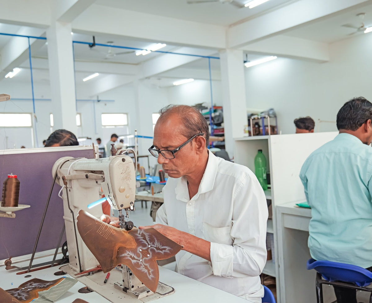 A sample maker stitching an embroidered Western boot shaft in a closing pod