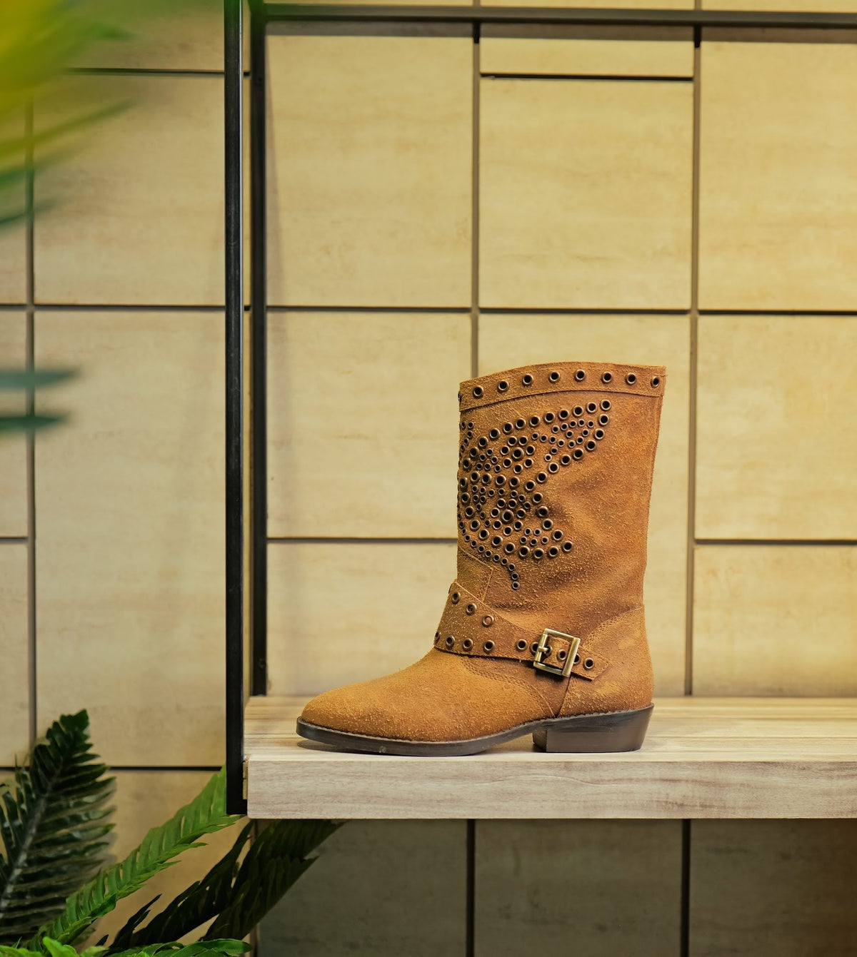 A studded suede mid-calf boot on a display shelf