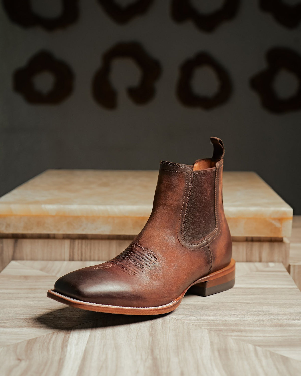 A tan leather Western Chelsea boot with elastic gussets on a stone plinth