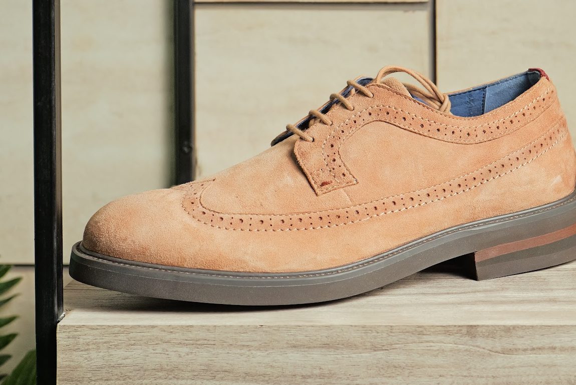 Tan suede wingtip brogue on a showroom shelf