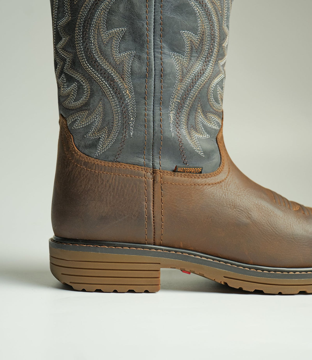 A Western work boot with a stitched blue shaft and a lugged sole, made by AFPL