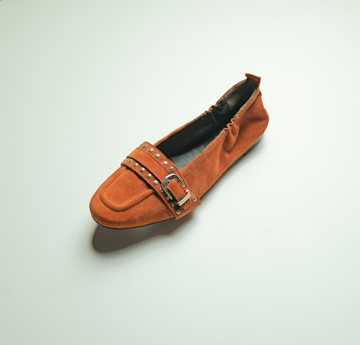 A women’s suede loafer with a studded buckle strap