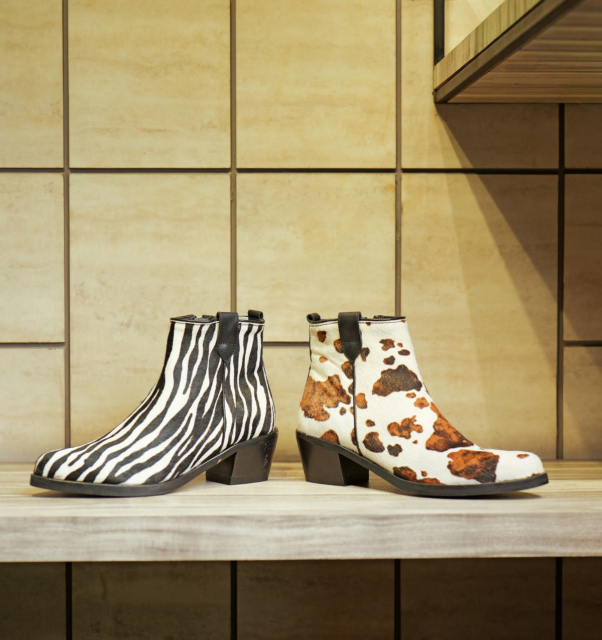 Zebra and cow print women’s ankle boots on a showroom shelf